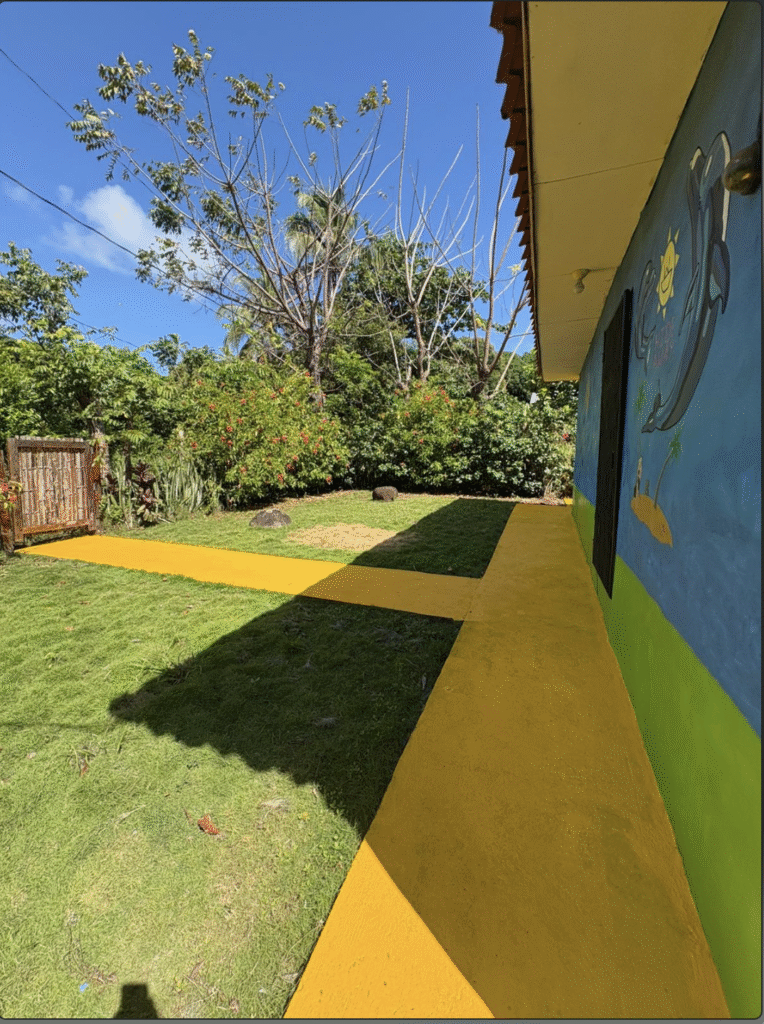 Colorful exterior of Little Corn Island House for rent with bright yellow path and tropical murals